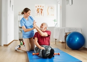Female physical therapy professional high fiving an older patient