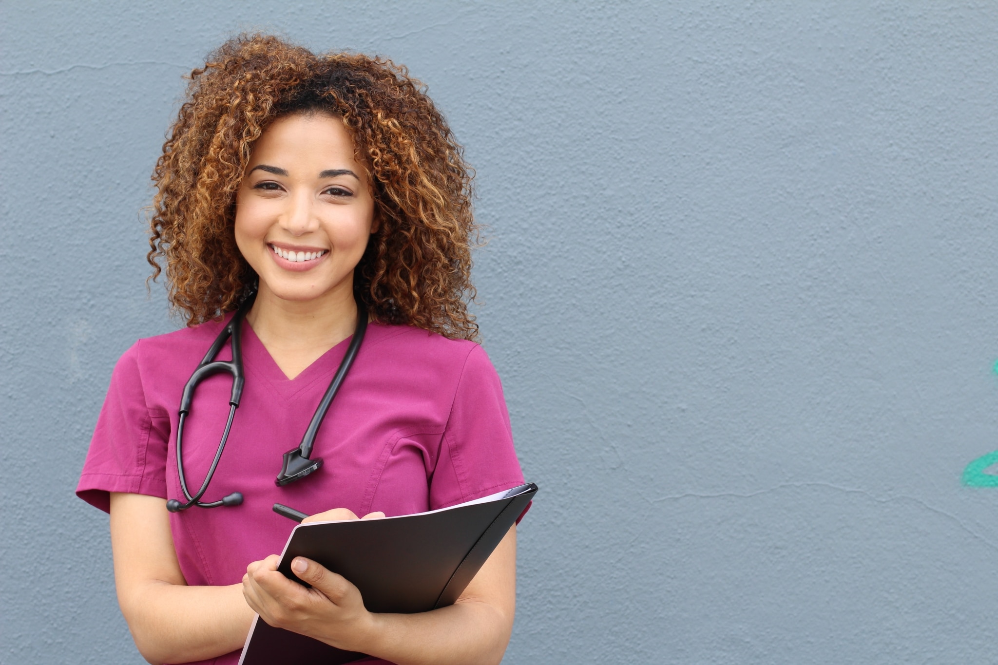 Smiling African-American nurse in pink scrubs